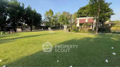 Spacious green garden area in a residential community with lush trees and modern houses.