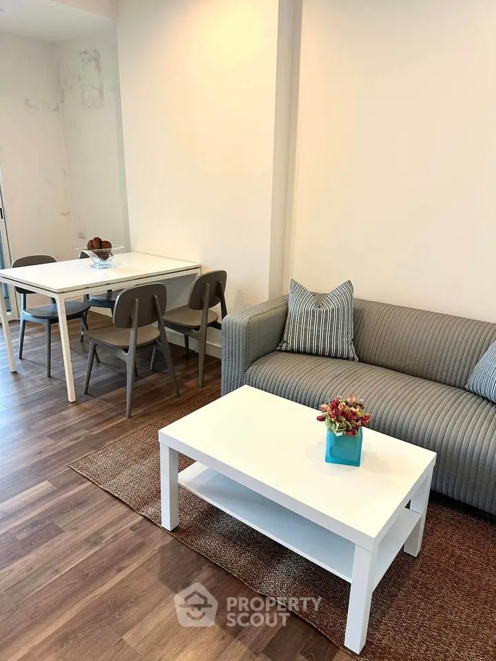 Modern living room with stylish furniture and dining area, featuring hardwood floors and cozy decor.