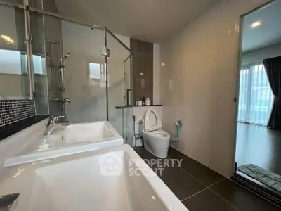 Modern bathroom with dual sinks and glass shower in luxury apartment