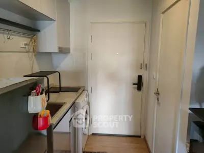 Compact kitchen with modern appliances and washing machine in cozy apartment.