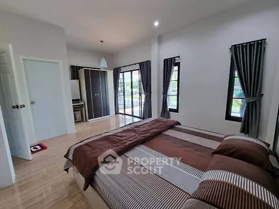 Spacious bedroom with modern decor and large windows offering natural light.