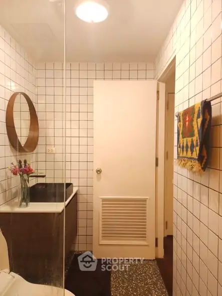 Chic modern bathroom with stylish round mirror and elegant tile design.