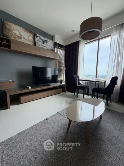 Modern living room with sleek furniture and large window offering city views.