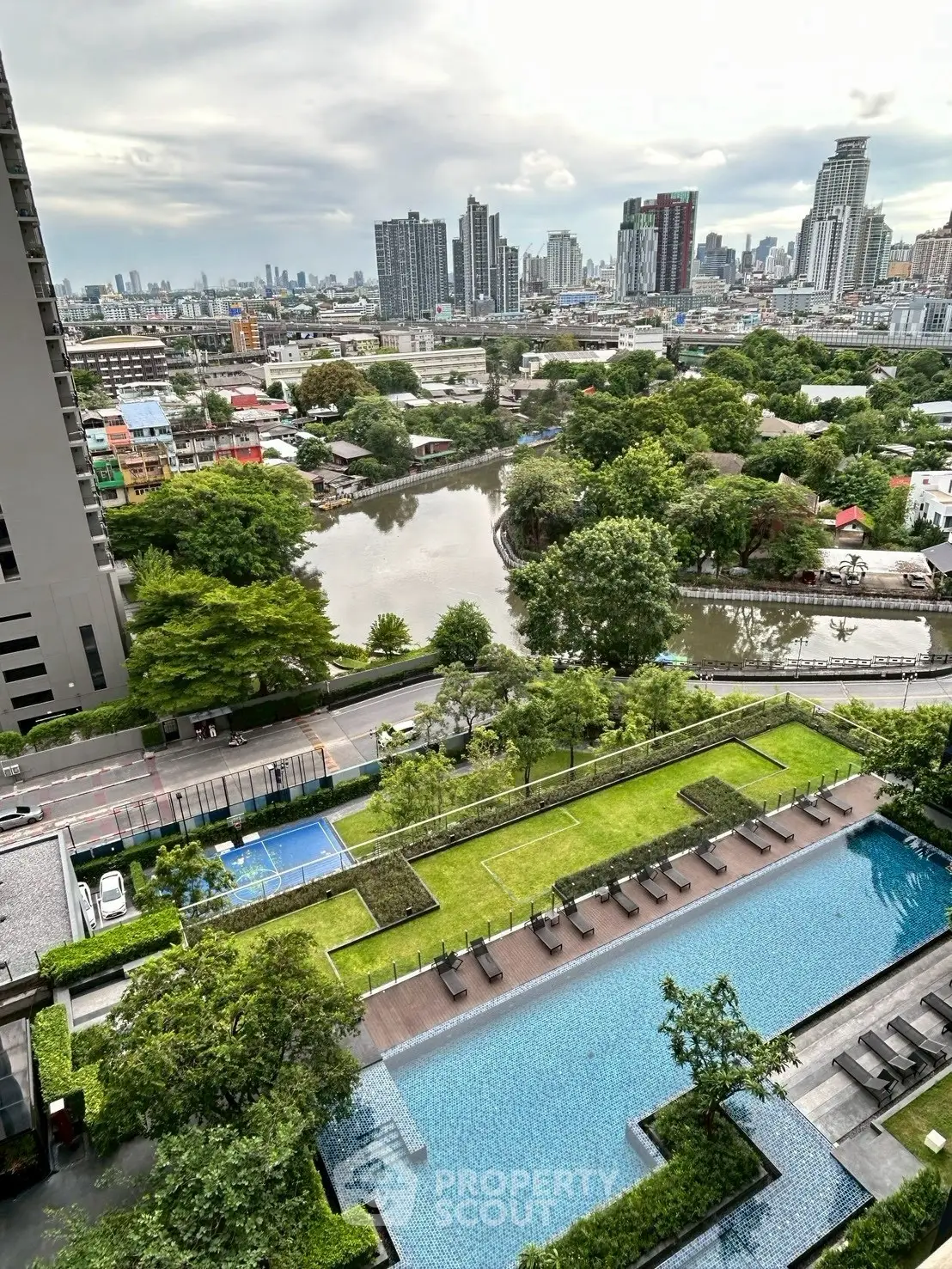 Stunning cityscape view from high-rise with pool and lush greenery, perfect for urban living.