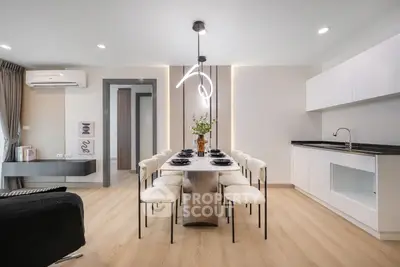 Modern dining area with sleek kitchen and stylish lighting in open-plan apartment.