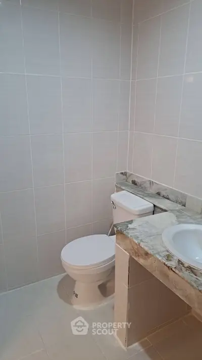 Modern bathroom with sleek marble countertop and tiled walls.