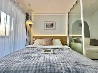 Cozy bedroom with modern decor and natural light, featuring a plush bed and stylish accents.