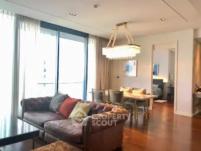 Luxurious living room with elegant chandelier and open view to bedroom, featuring stylish furniture and hardwood floors.