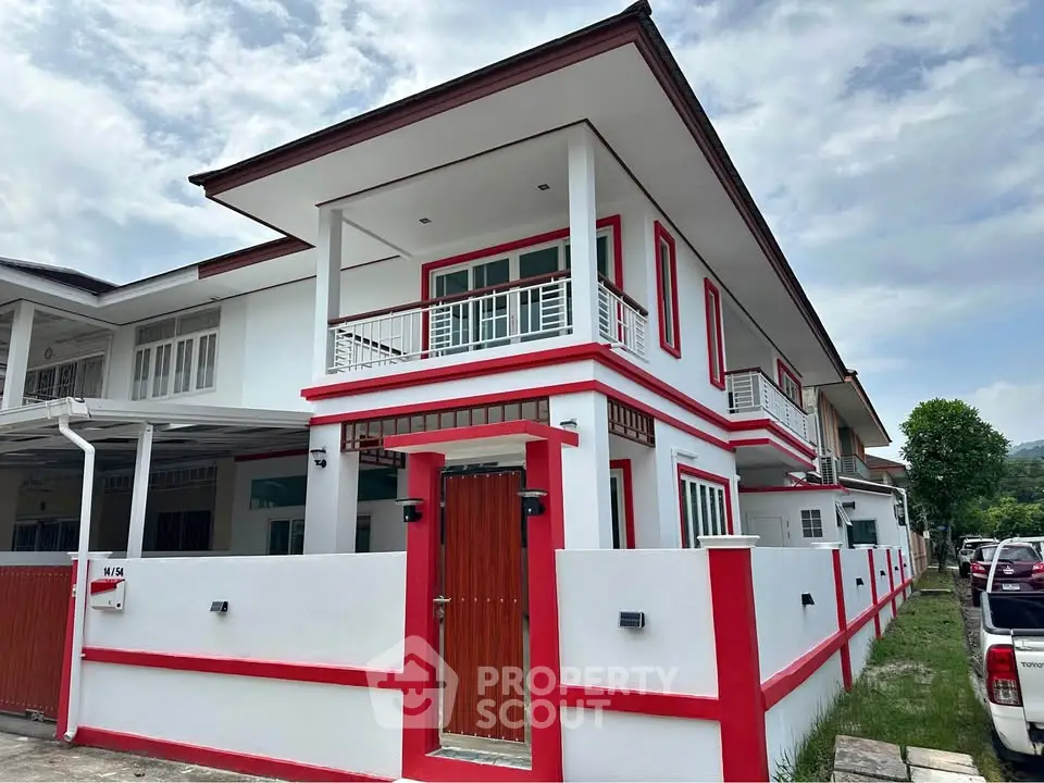 Modern two-story house with red and white exterior, featuring a spacious balcony and stylish design.