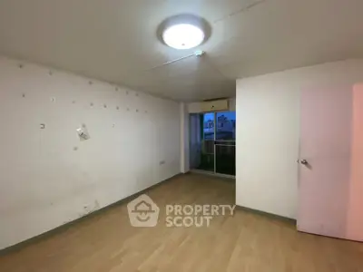 Spacious empty room with wooden flooring and balcony access, ideal for customization.