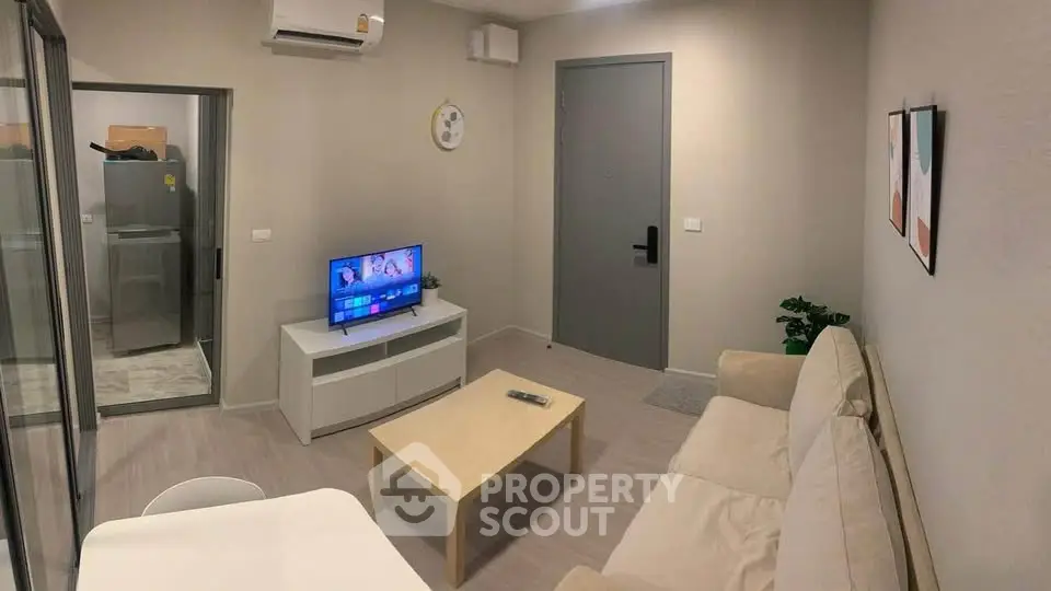 Modern living room with cozy beige sofa, flat-screen TV, and minimalist decor