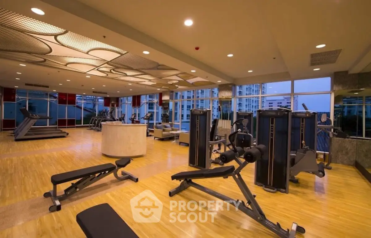 Spacious modern gym with state-of-the-art equipment and city view windows.