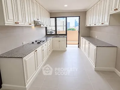 Spacious kitchen with elegant cabinetry and city view balcony access.