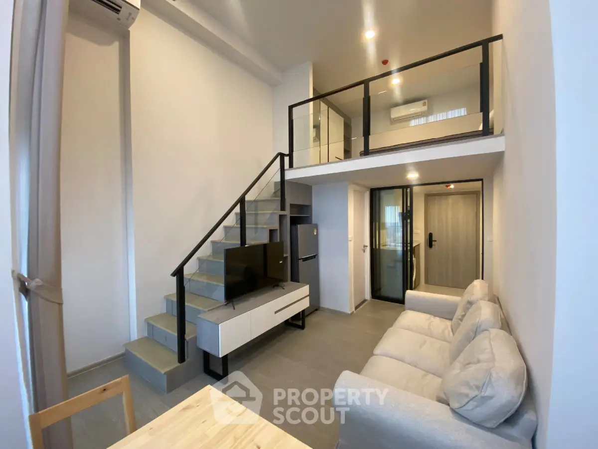 Modern loft-style living room with mezzanine, sleek staircase, and cozy seating area.