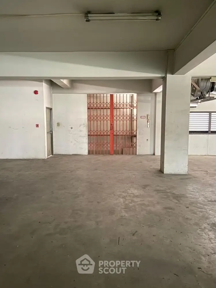 Spacious industrial-style interior with concrete flooring and metal gate, ideal for storage or workshop.