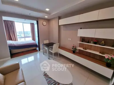 Modern living room with open layout and bedroom view, featuring sleek furniture and cityscape window.