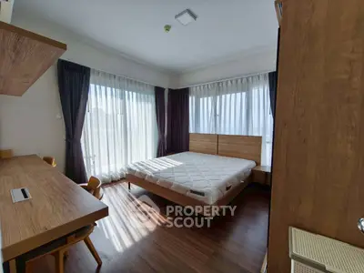 Modern bedroom with wooden furniture and large windows for natural light