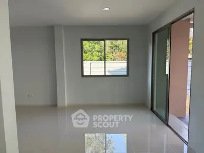 Spacious modern living room with large windows and sliding glass doors opening to a serene outdoor view.