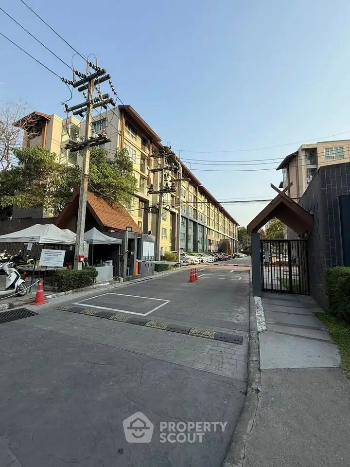 Modern apartment building exterior with gated entrance and street view, showcasing urban living.