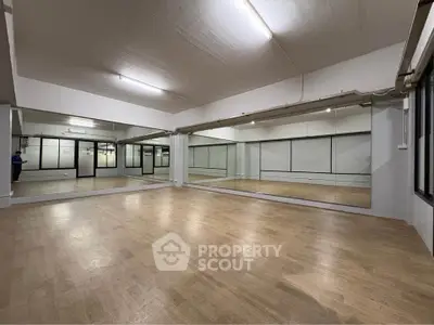 Spacious mirrored studio with wooden flooring, ideal for dance or fitness activities.