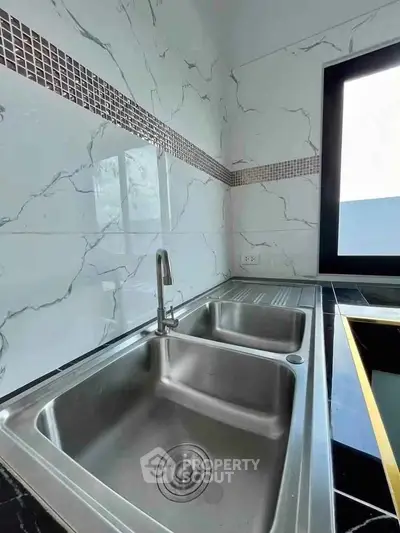 Modern kitchen with sleek double sink and marble backsplash