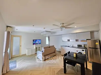 Modern open-plan living room with kitchen, featuring sleek appliances and stylish decor.