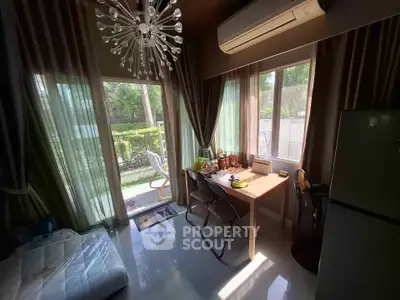 Cozy living room with modern chandelier and garden view, featuring a compact dining area and large windows.