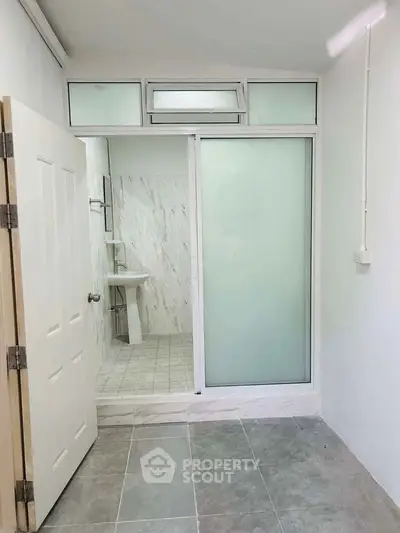 Modern bathroom with frosted glass door and sleek white fixtures