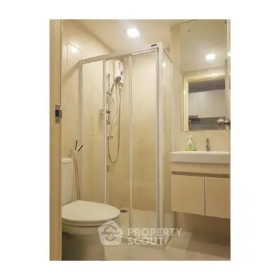 Modern bathroom with glass shower enclosure and sleek vanity in a contemporary apartment.