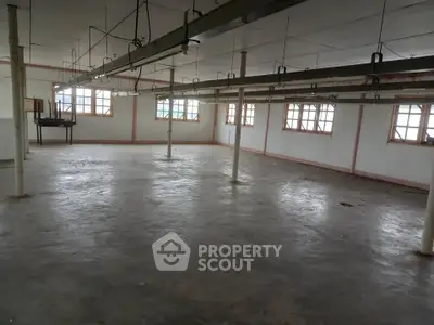 Spacious industrial warehouse with large windows and open floor plan, ideal for storage or manufacturing.