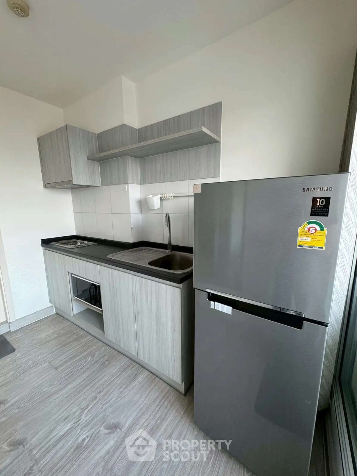 Modern kitchen with sleek cabinetry and stainless steel fridge in a compact layout.