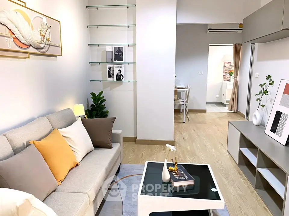 Modern living room with stylish decor and open layout, featuring cozy seating and elegant shelving.