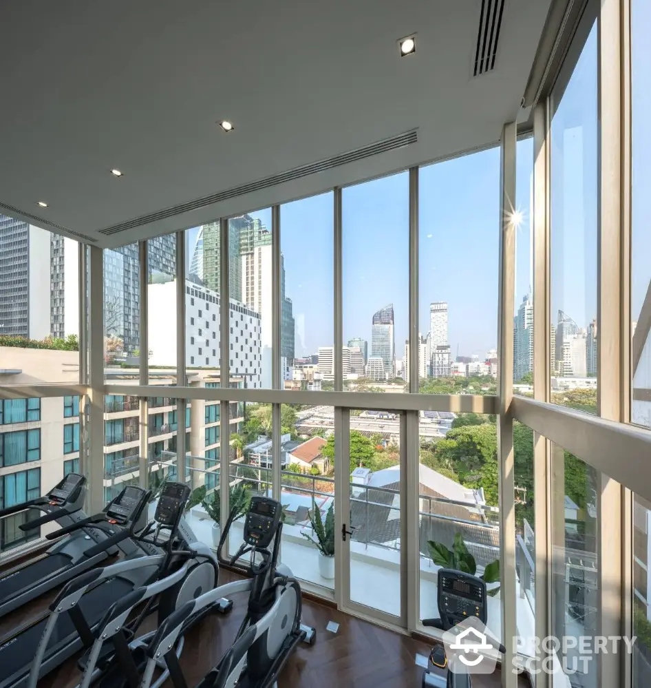 Luxurious gym with panoramic city views and modern fitness equipment in high-rise building.