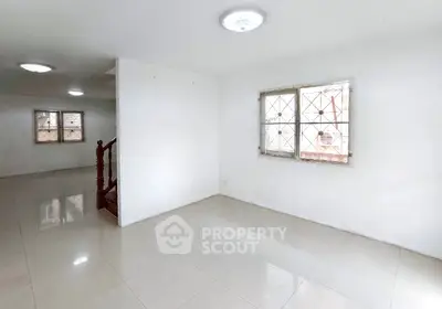 Spacious white-walled room with tiled flooring and natural light