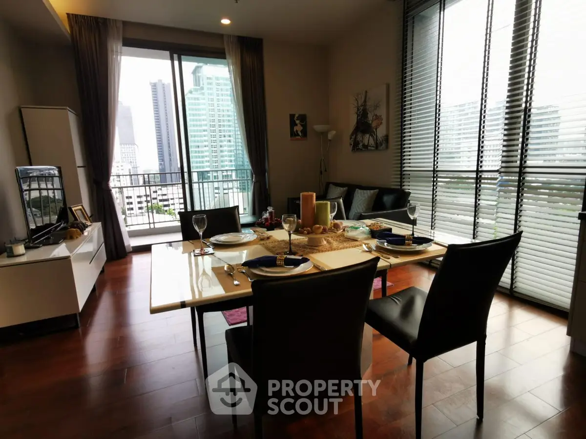 Modern dining area with city view, elegant table setting, and large windows in a high-rise apartment.