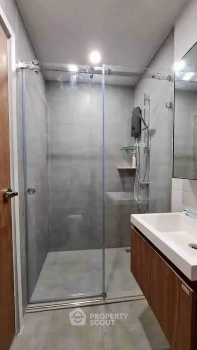 Modern bathroom with glass shower enclosure and sleek vanity in contemporary apartment.