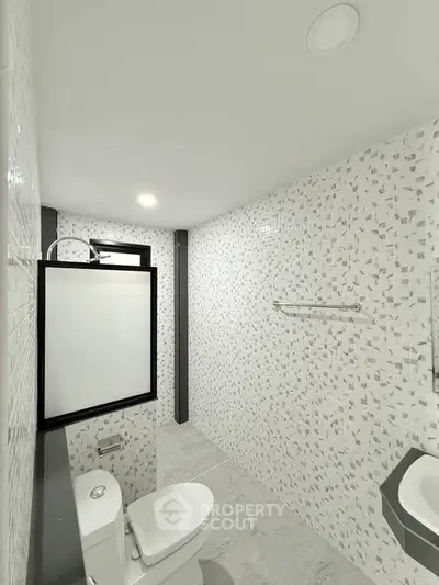 Modern minimalist bathroom with sleek white tiles and contemporary fixtures.