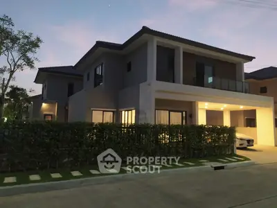 Modern two-story house with spacious driveway and lush greenery at dusk