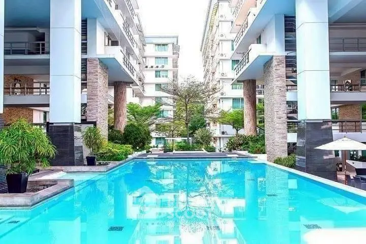 Luxurious modern apartment complex with stunning pool and lush greenery.