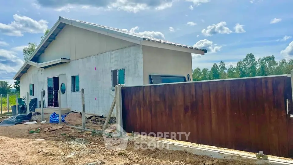 Charming rural home with spacious yard and modern gate under a clear blue sky.