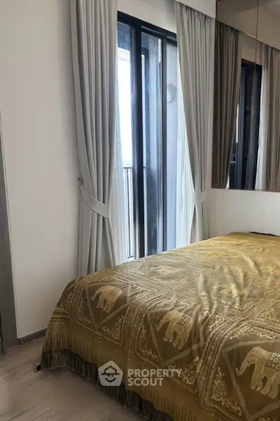 Cozy bedroom with elegant curtains and a stylish bedspread, featuring a view of the balcony.