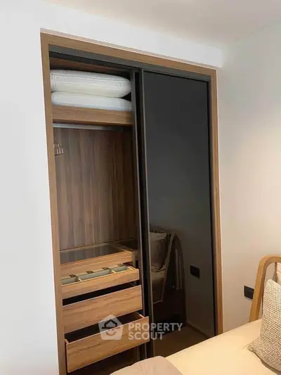 Modern bedroom with sleek built-in wardrobe featuring sliding doors and wooden finish.