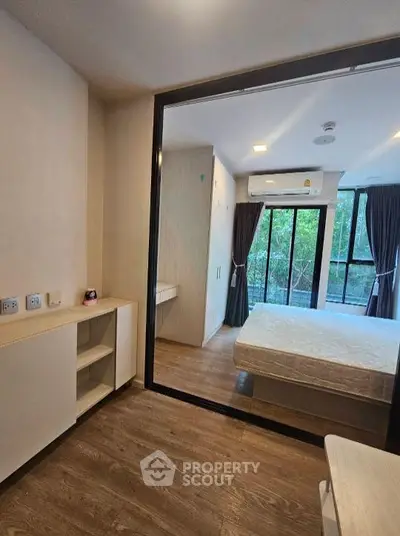 Modern bedroom with large windows and balcony view, featuring sleek wooden flooring and minimalist design.