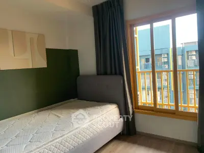Cozy bedroom with modern decor and large window offering natural light.