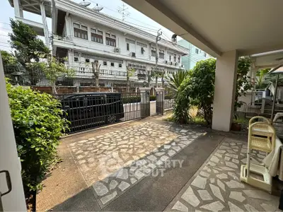 Charming residential entrance with lush greenery and stone pathway, offering a welcoming outdoor space.