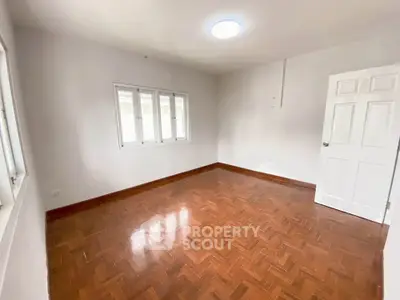 Spacious empty room with wooden flooring and white walls, ideal for customization.