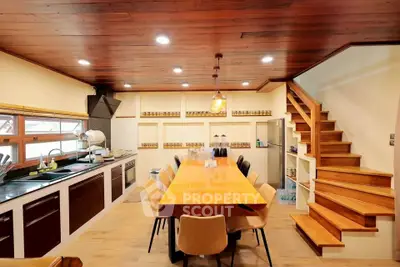 Spacious kitchen with wooden dining table and modern cabinetry, perfect for family gatherings.