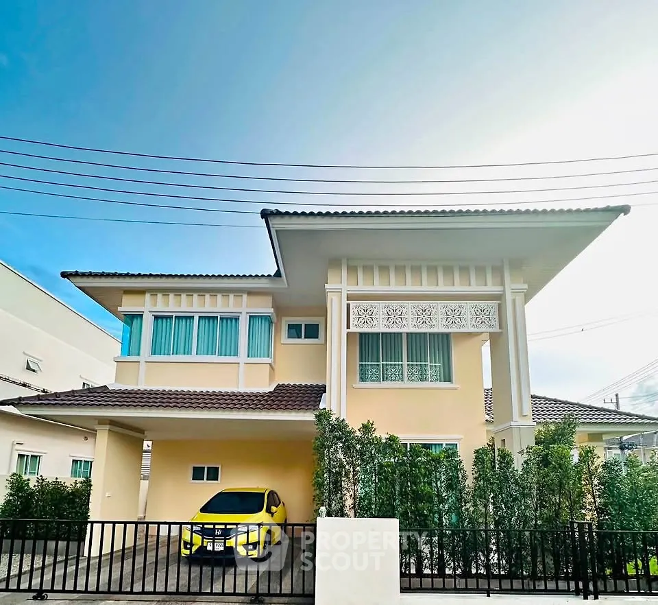 Charming two-story house with modern design and lush greenery, featuring a secure gated driveway and vibrant exterior.