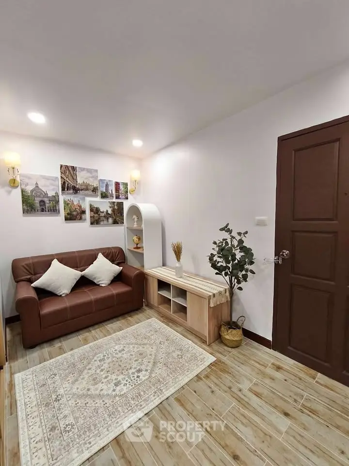 Cozy living room with brown sofa, decorative wall art, and wooden flooring