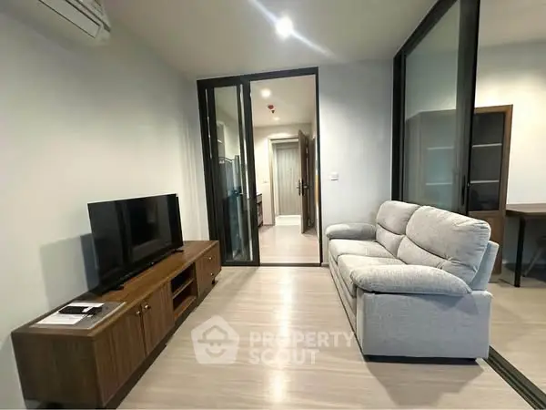 Modern living room with sleek furniture and glass partition in a cozy apartment.
